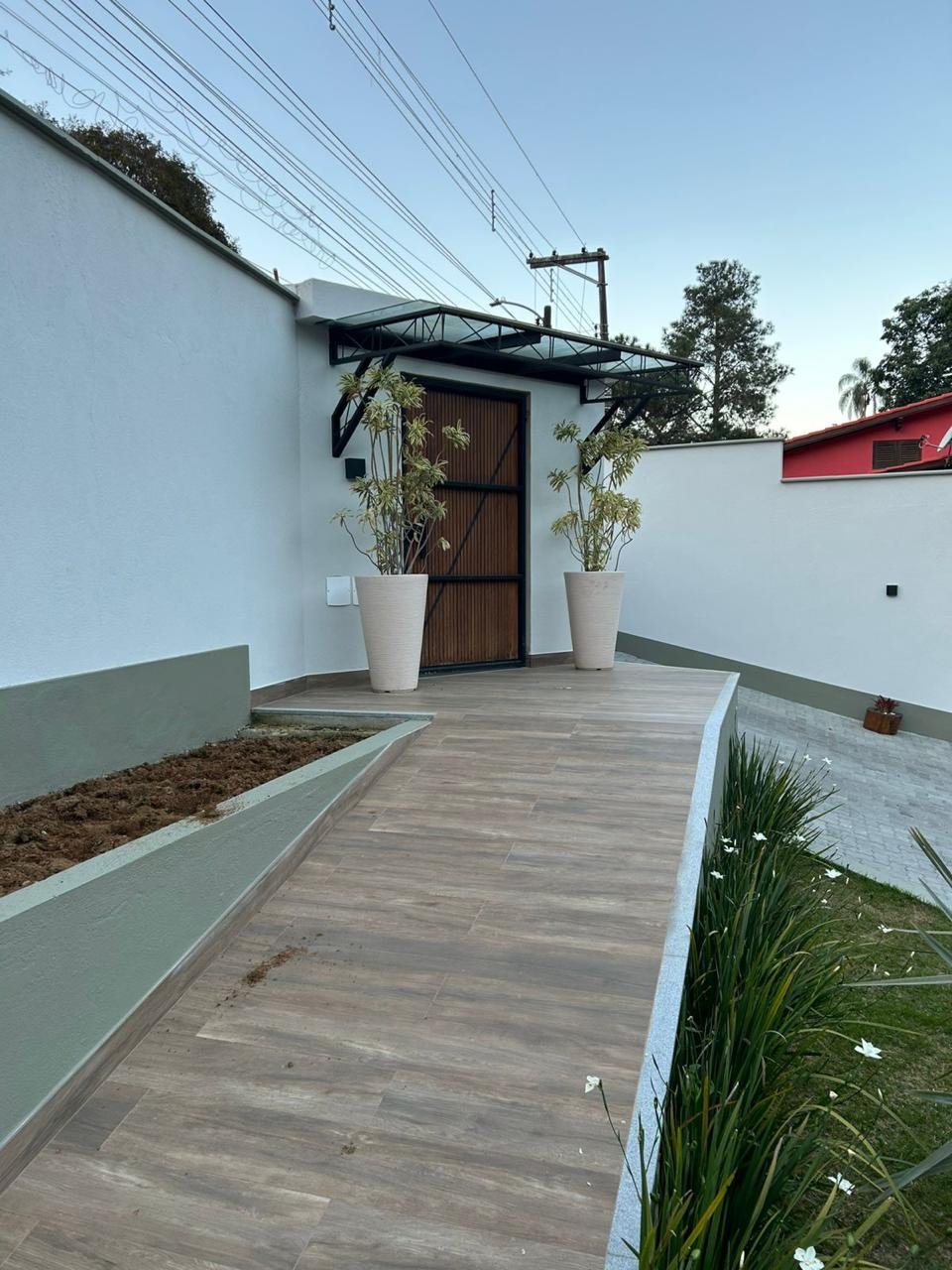 Entrada de casa com muros brancos e rodapé verde